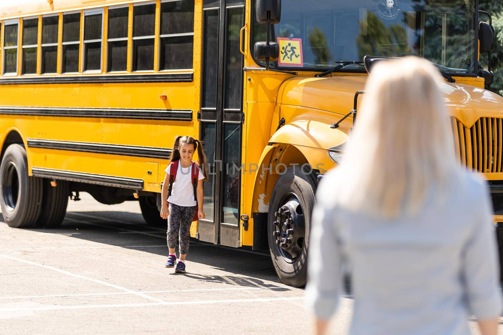 Mother brings her daughter to school near the school bus. back to school