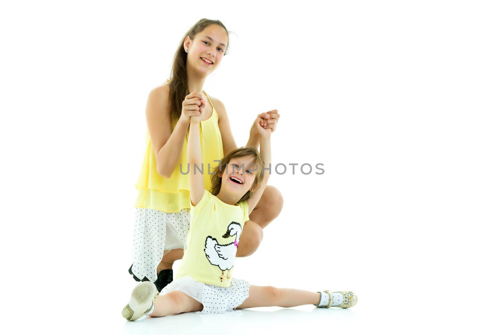 Two older and younger girls, two sisters fun posing in the studio. The concept of family, friendship. Isolated on white background.