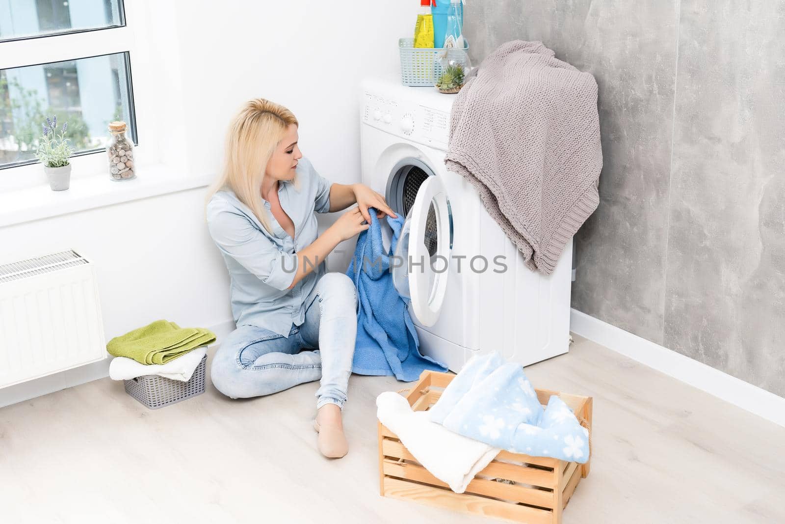 A young housewife with washing machine and clothes. Washing day.