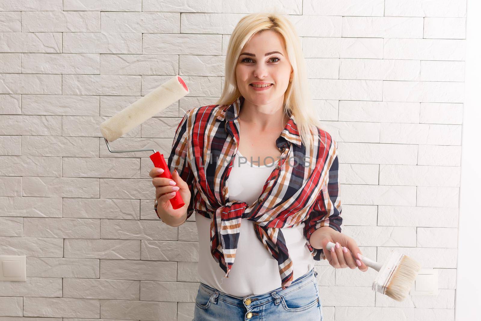 Beautiful young woman painting wall in room