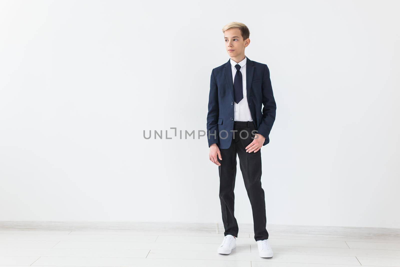 Portrait of stylish school boy teenager in white shirt and jacket against white background with copy space