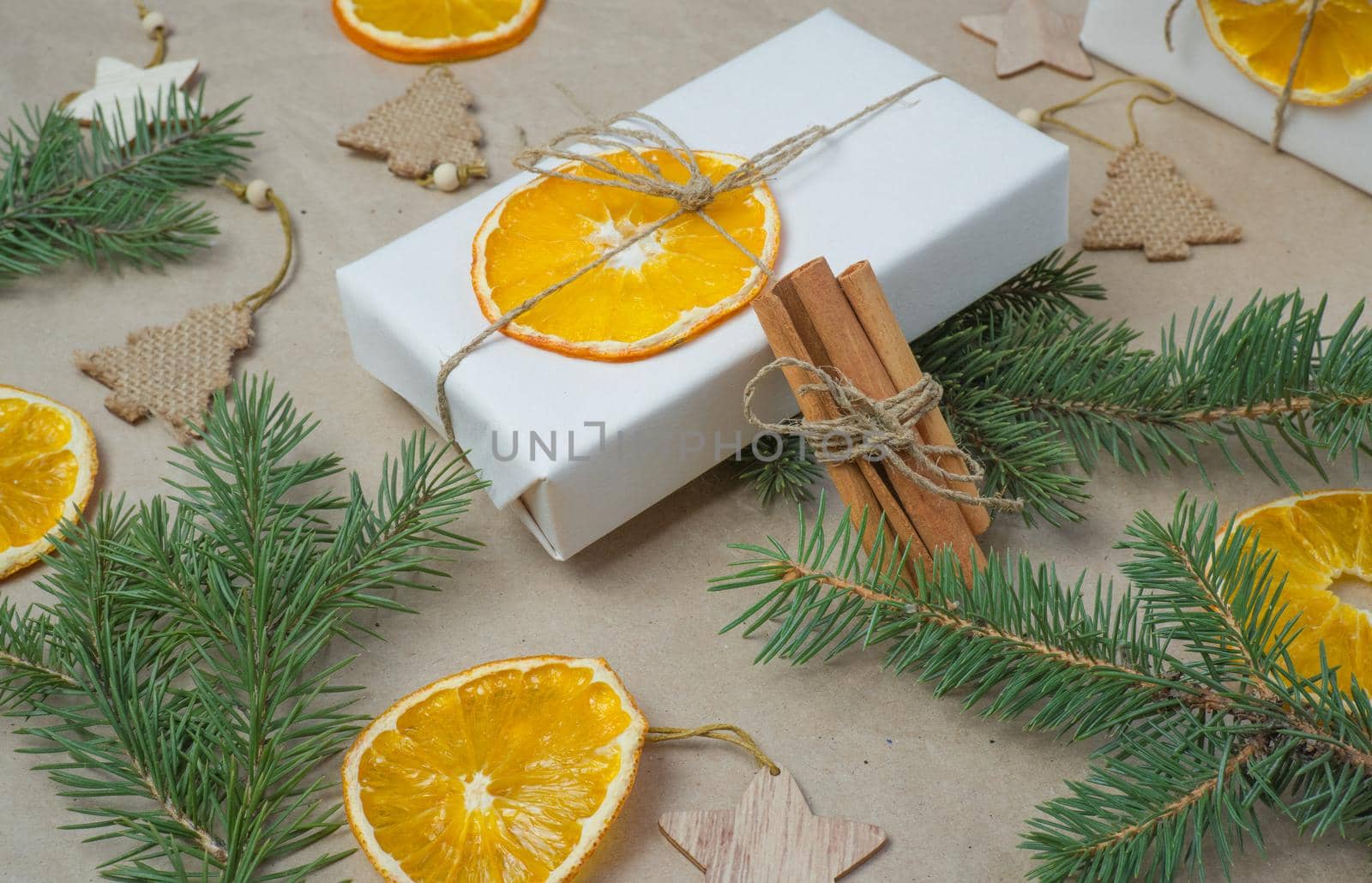 New Year's composition. On beige craft paper, gift boxes, dry orange slices, pine cones, cinnamon, cloves, spruce branches. Cozy Christmas concept. by Ekaterina34