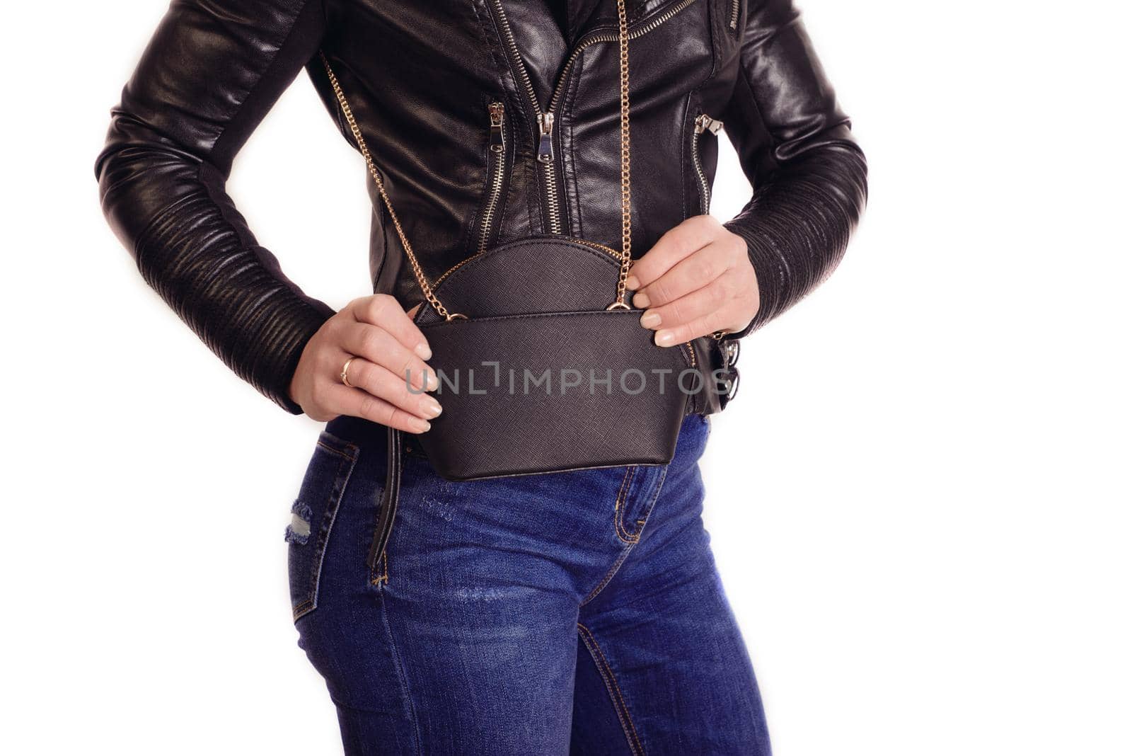 Trendy young girl in black jacket and jeans holding black fringe handbag. Fashion details