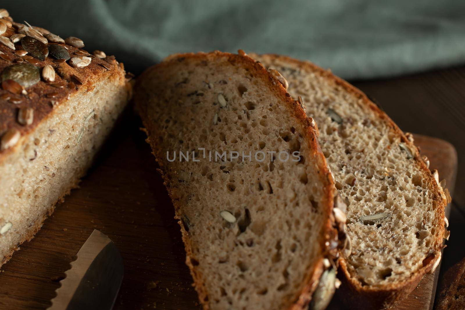Sliced Homemade Whole Grain Bread with Seeds on a Cutting Board, close up by galsand