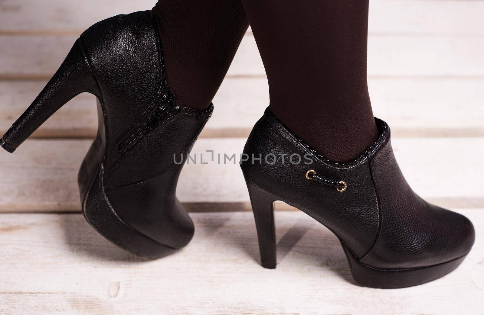 autumn black female high-heeled shoes on a white wooden floor.