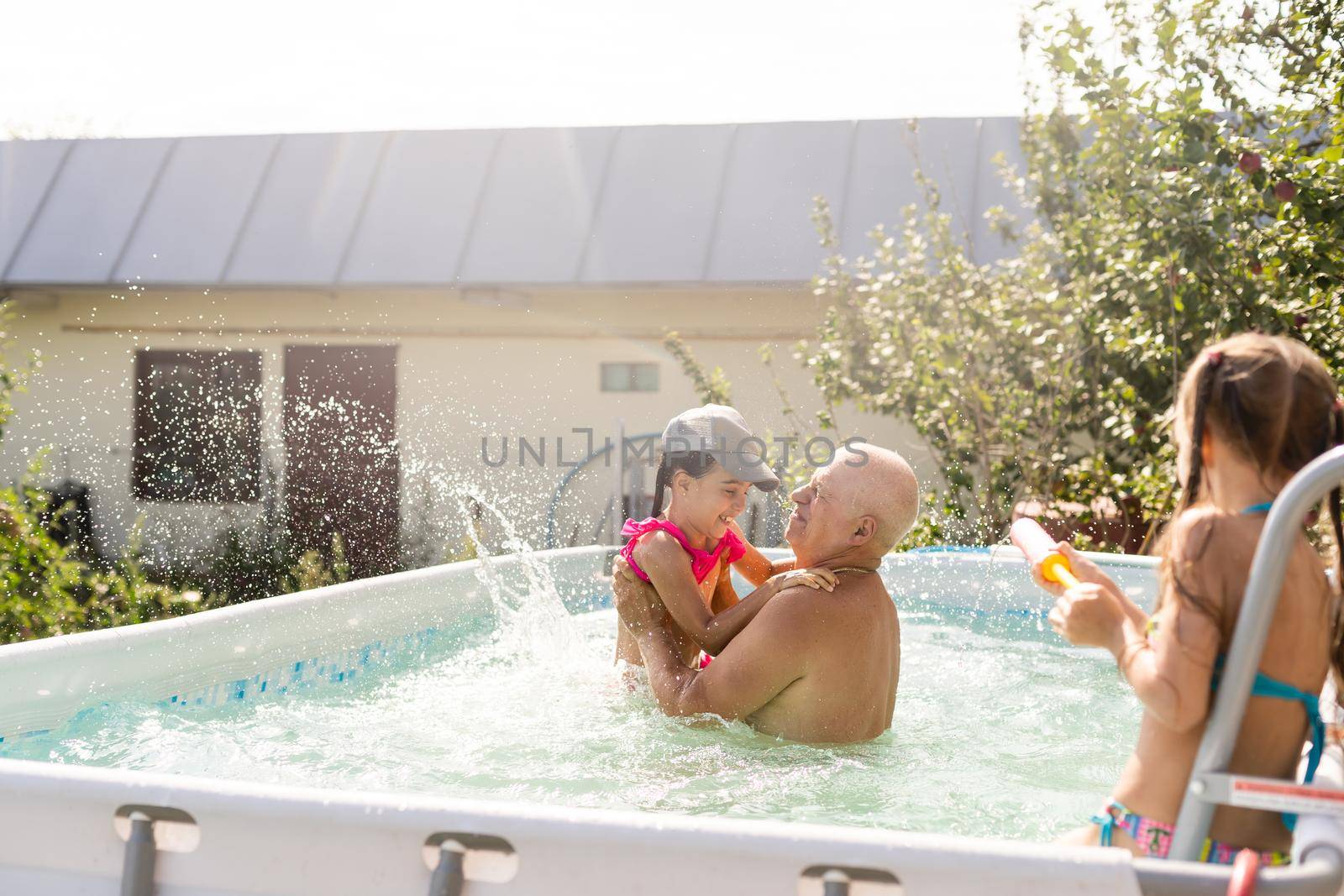 Portrait of a happy grandfather with grandchildren in pool