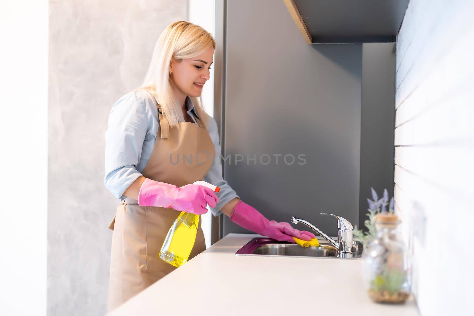 Young woman doing housework, cleaning the kitchen