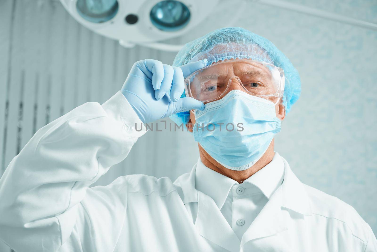 Serious older man surgeon in protective uniform in operating room