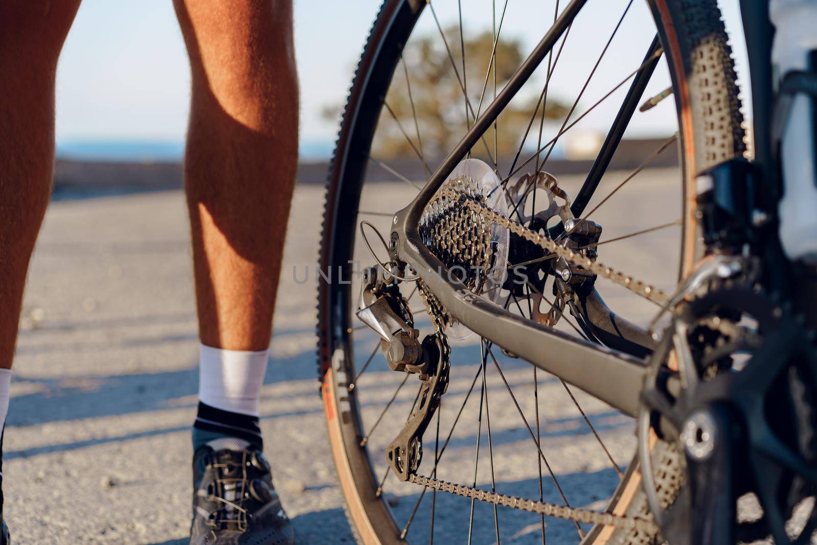 Cyclist man feet and bike wheel on coastal road close up