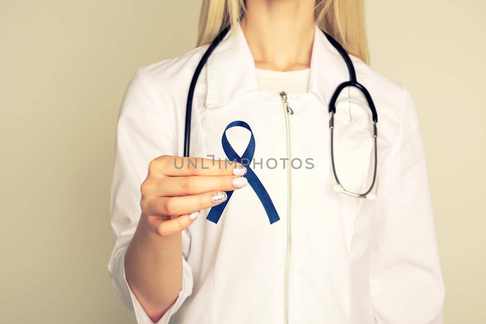 Doctor hands holding blue ribbon, diabetes and Colorectal Cancer Awareness by zartarn