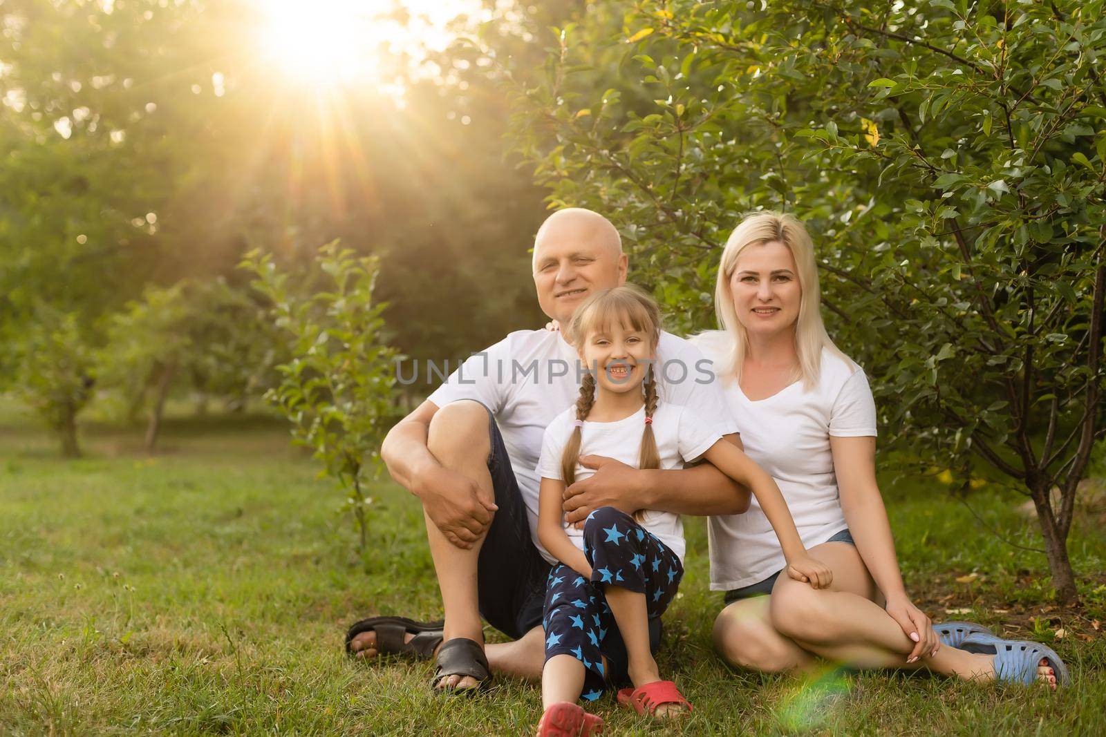 Portrait of cheerful extended family sitting in the park by Andelov13