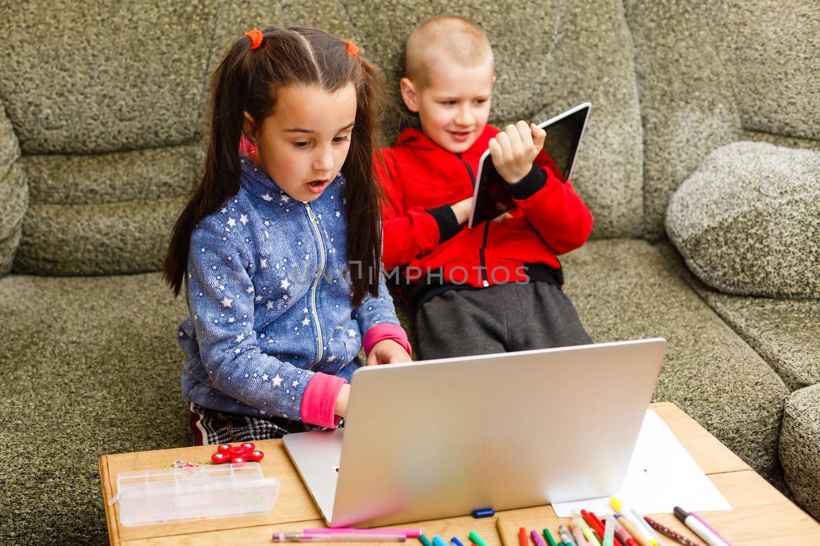 Two beautiful cute happy smiling children, a boy and a girl, use laptop for distance learning or entertainment. by Andelov13