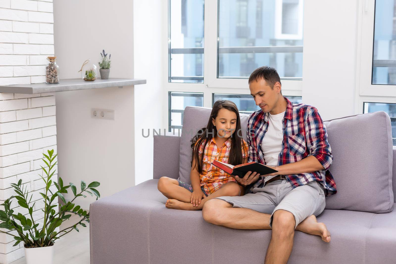 a young father with his little daughter reads the Bible