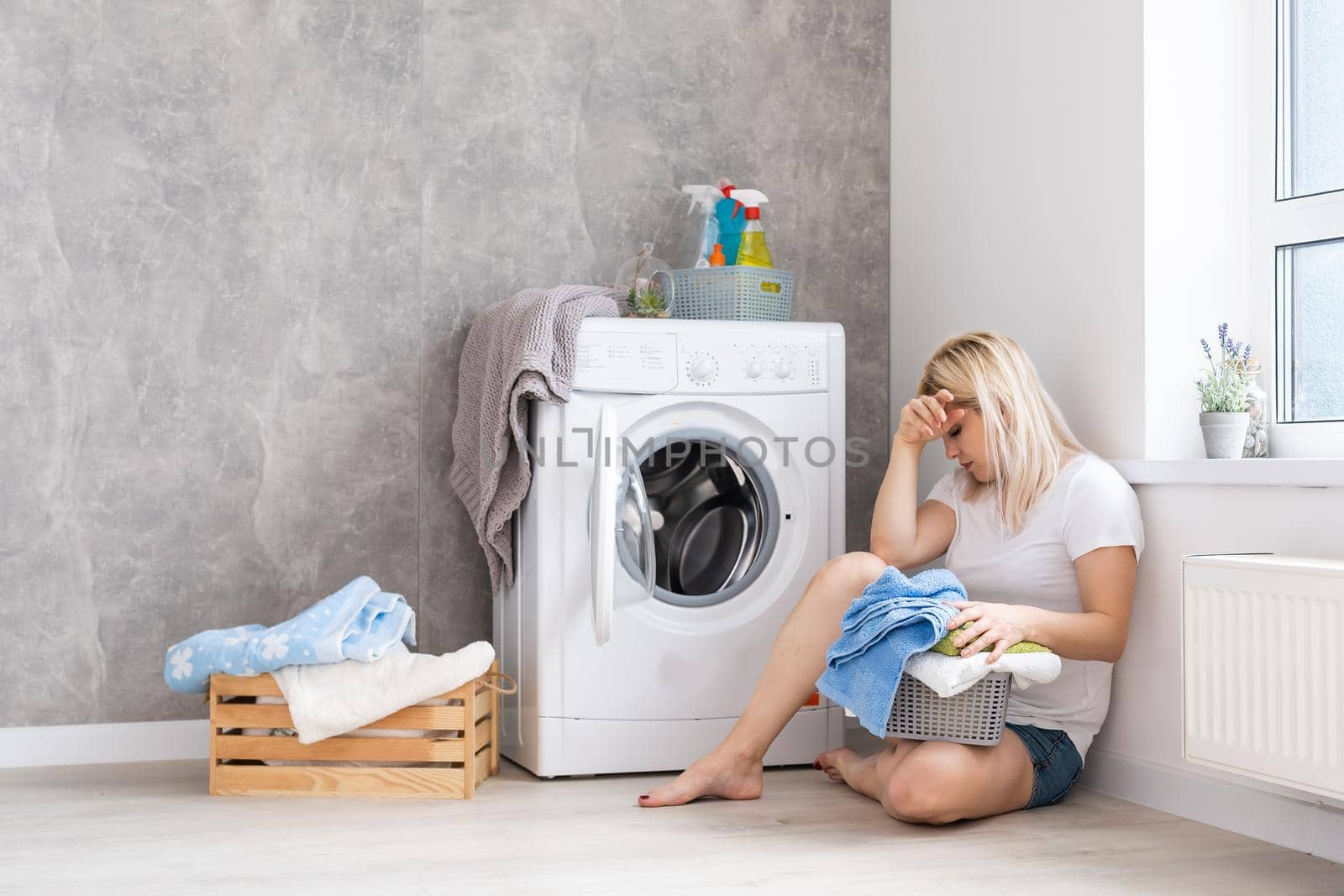 A young housewife with washing machine and clothes. Washing day.