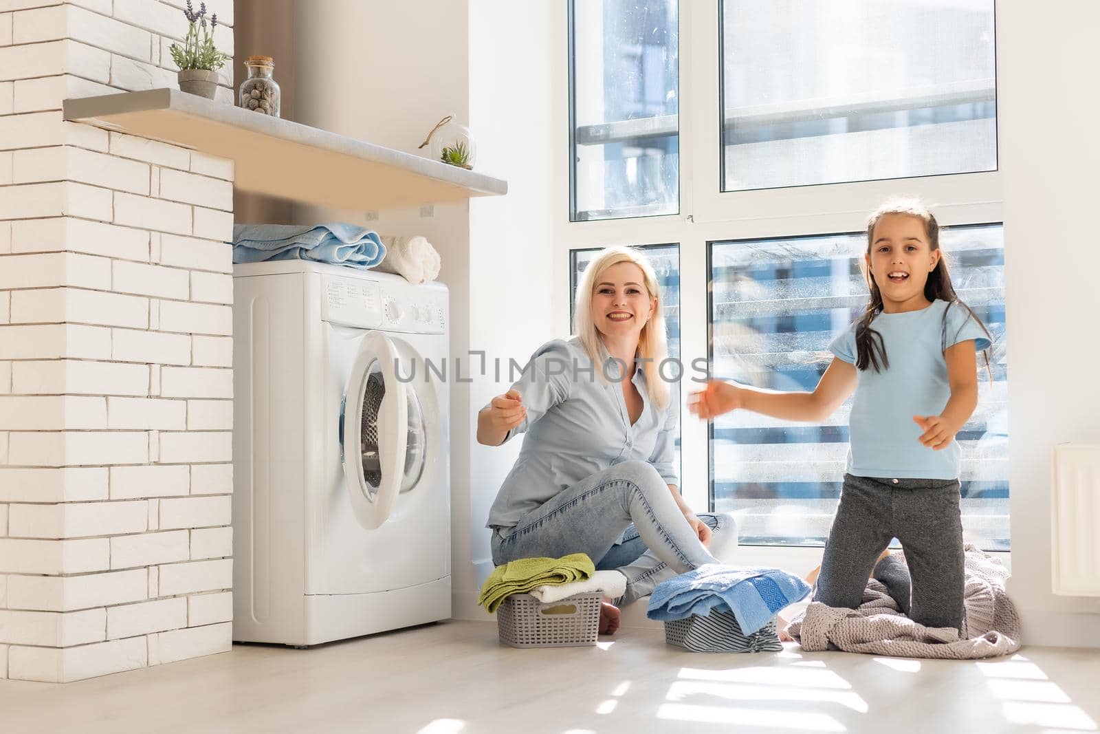 Young housewife and little girl doing laundry together