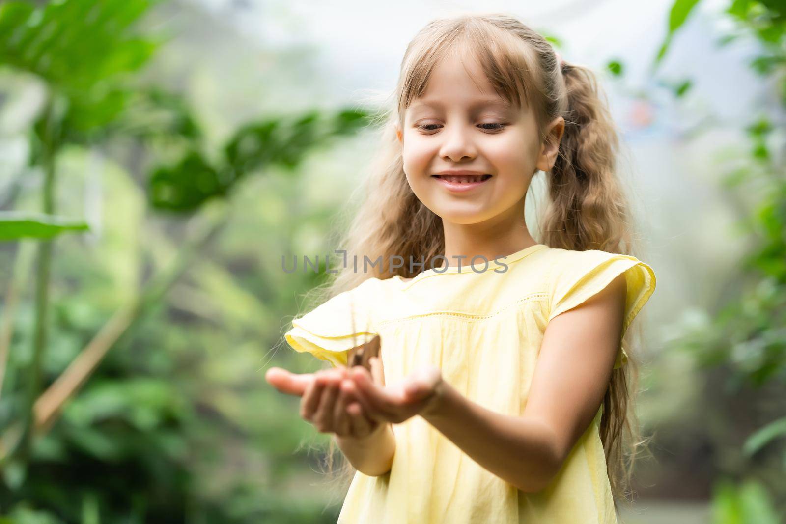 Little girl holding butterfly in her hand.