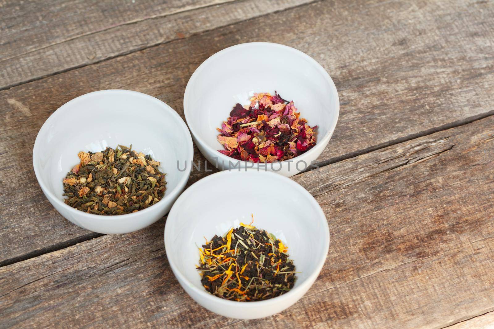 Aromatic dry tea in bowls on wooden background