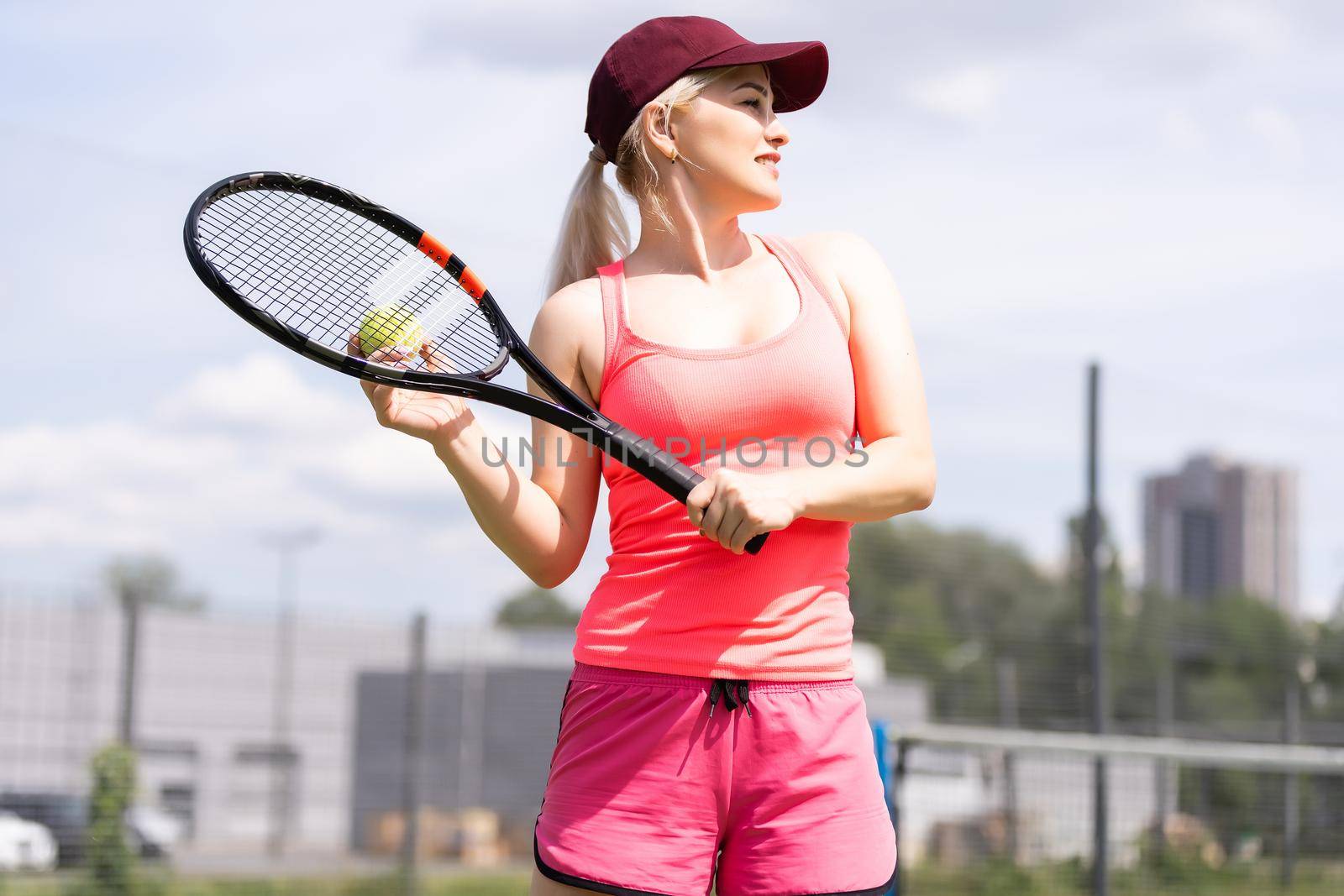 Woman playing tennis holding a racket and smiling