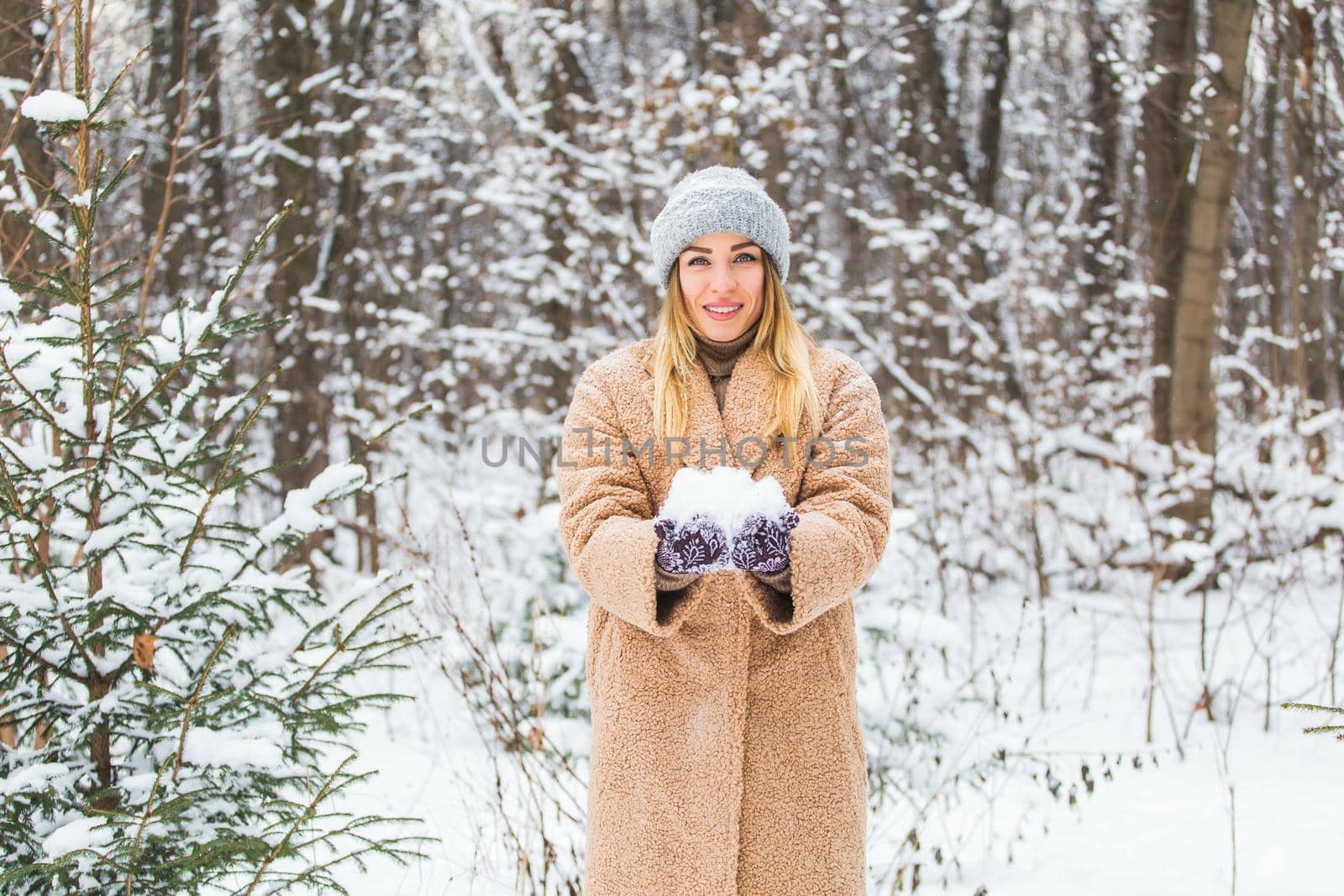 Young woman throwing snow in the air at sunny winter day, she is happy and fun