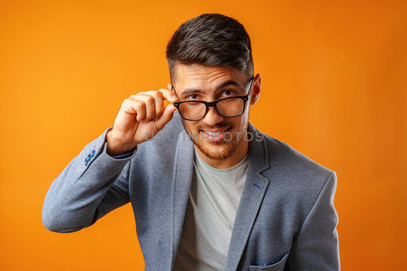 Portrait of a young smart man businessman wearing glasses against yellow background