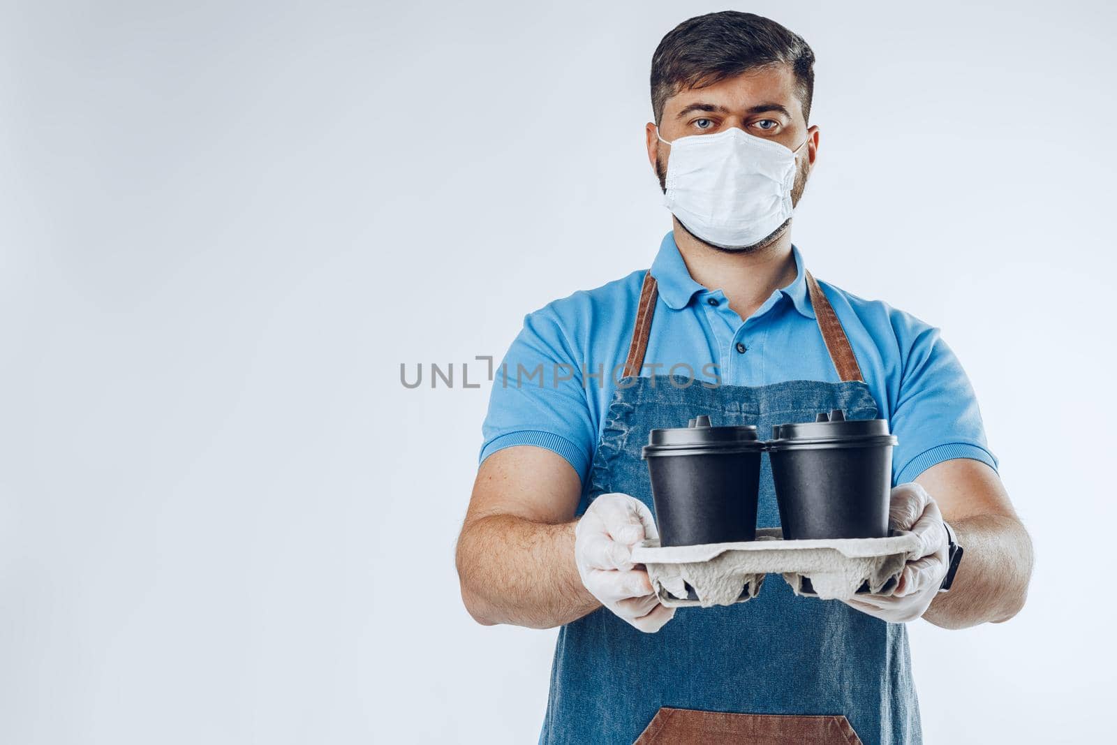 Man in medical gloves giving black takeaway coffee cups. Safe service while covid-19 coronavirus pandemic