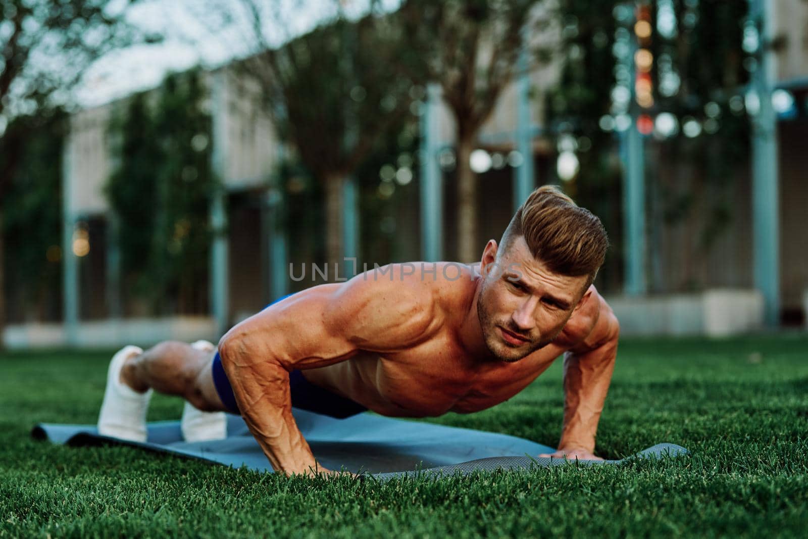 athletic man with pumped up muscular body in the park doing exercise. High quality photo