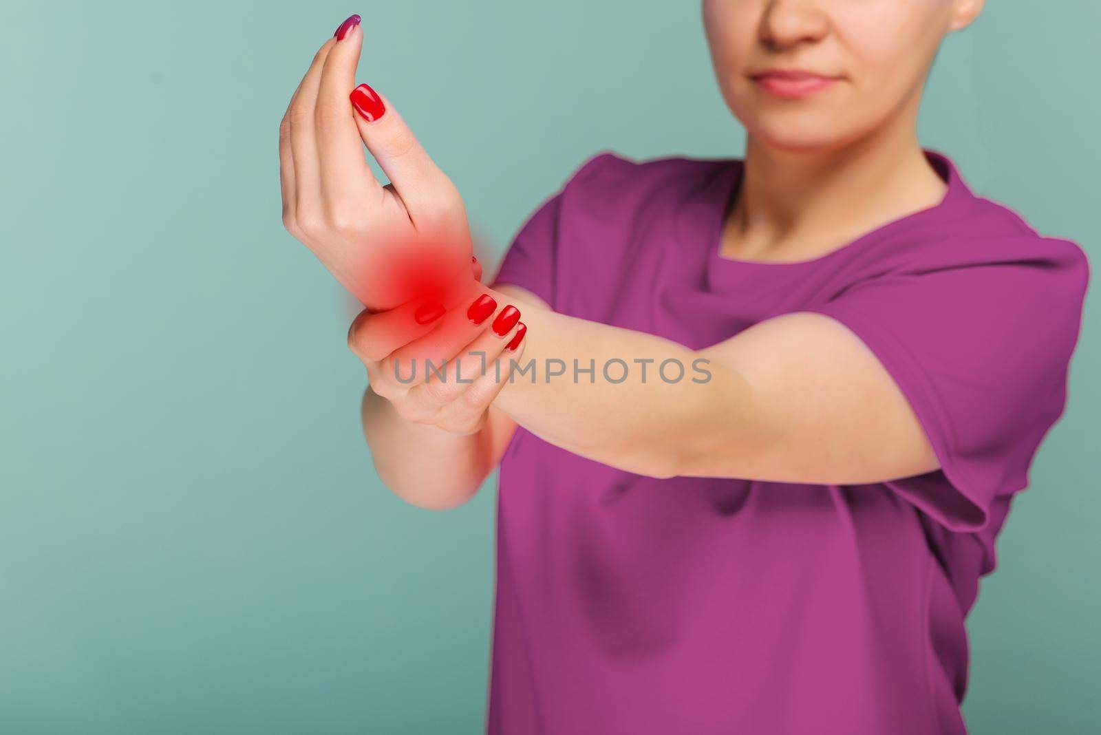 A woman massaging her painful hand isolated on a blue background