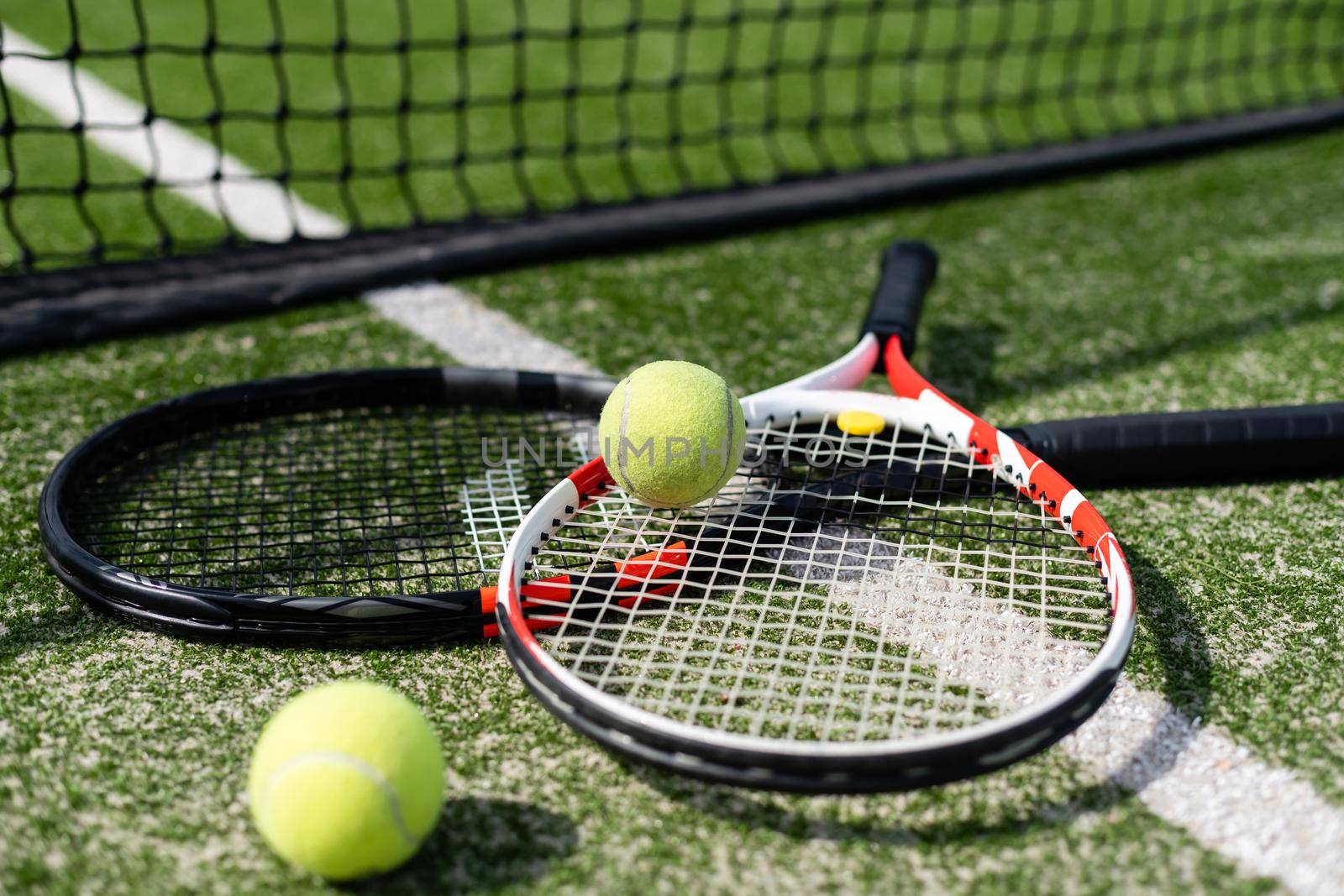A tennis racket and new tennis ball on a freshly painted tennis court