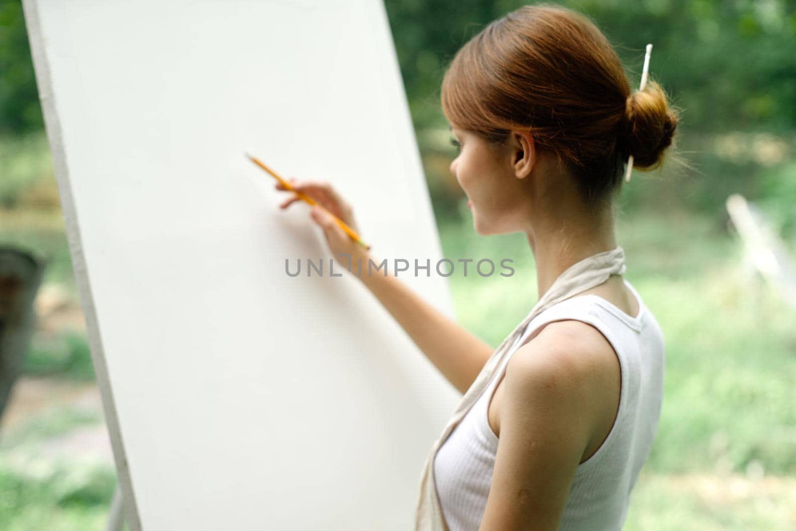 an artist in nature draws on an easel with a pencil by Vichizh