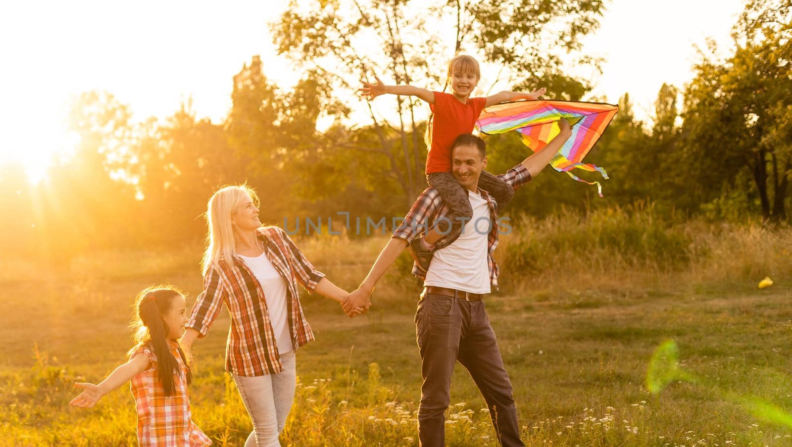 Happy family father of mother and daughters launch a kite on nature at sunset by Andelov13