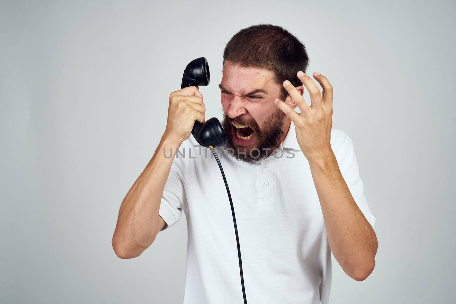 emotional bearded man talking on the phone light background. High quality photo