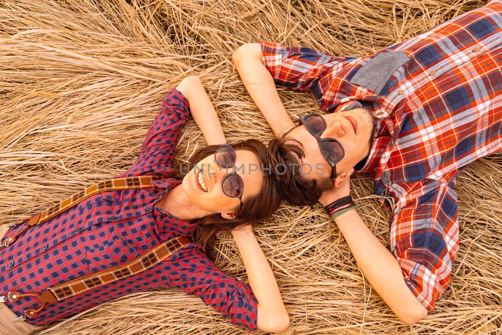 Young couple rests on dry grass by alexAleksei