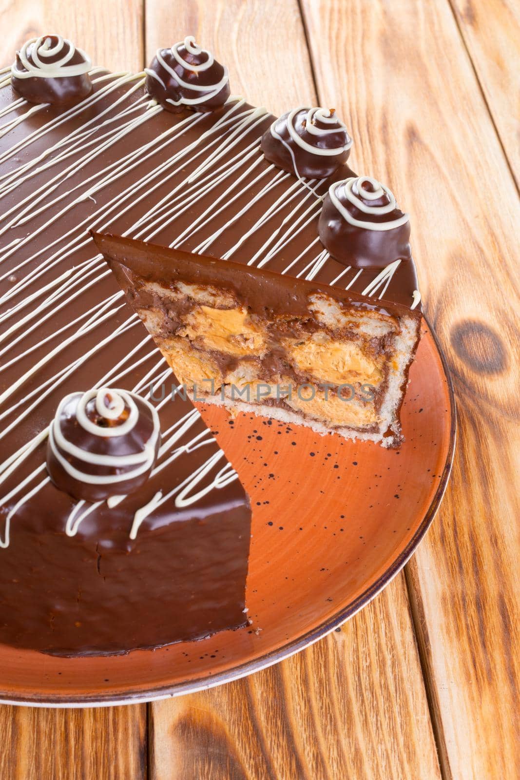 Cut chocolate cake on plate on wooden table close up