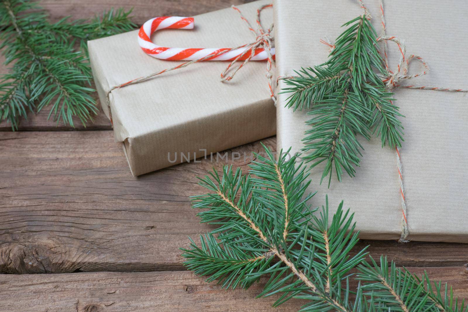 Christmas presents or gift box wrapped in kraft paper with decorations and fir branch on rustic wooden background