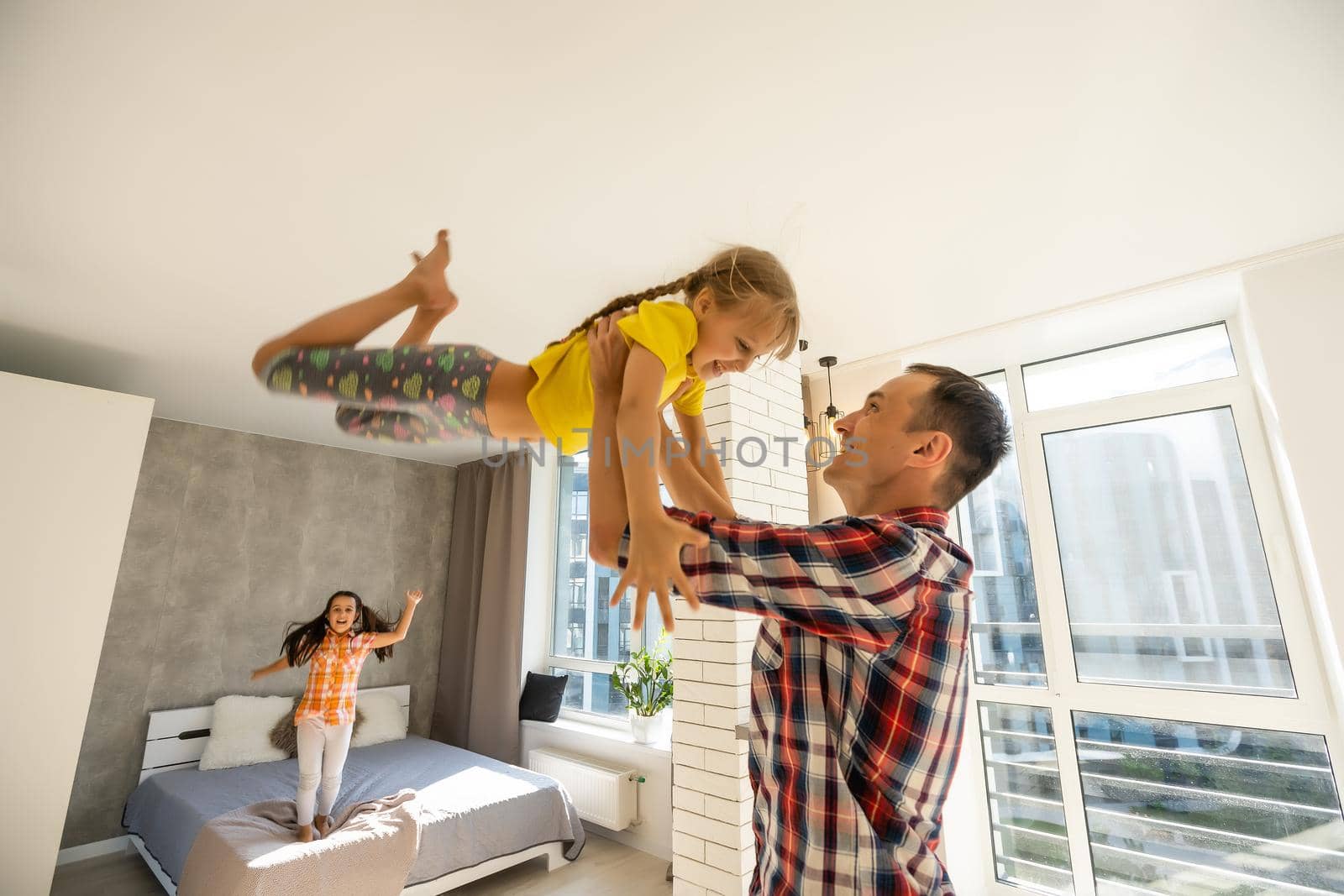 happy father and two children playing and cuddling at home on floor by Andelov13