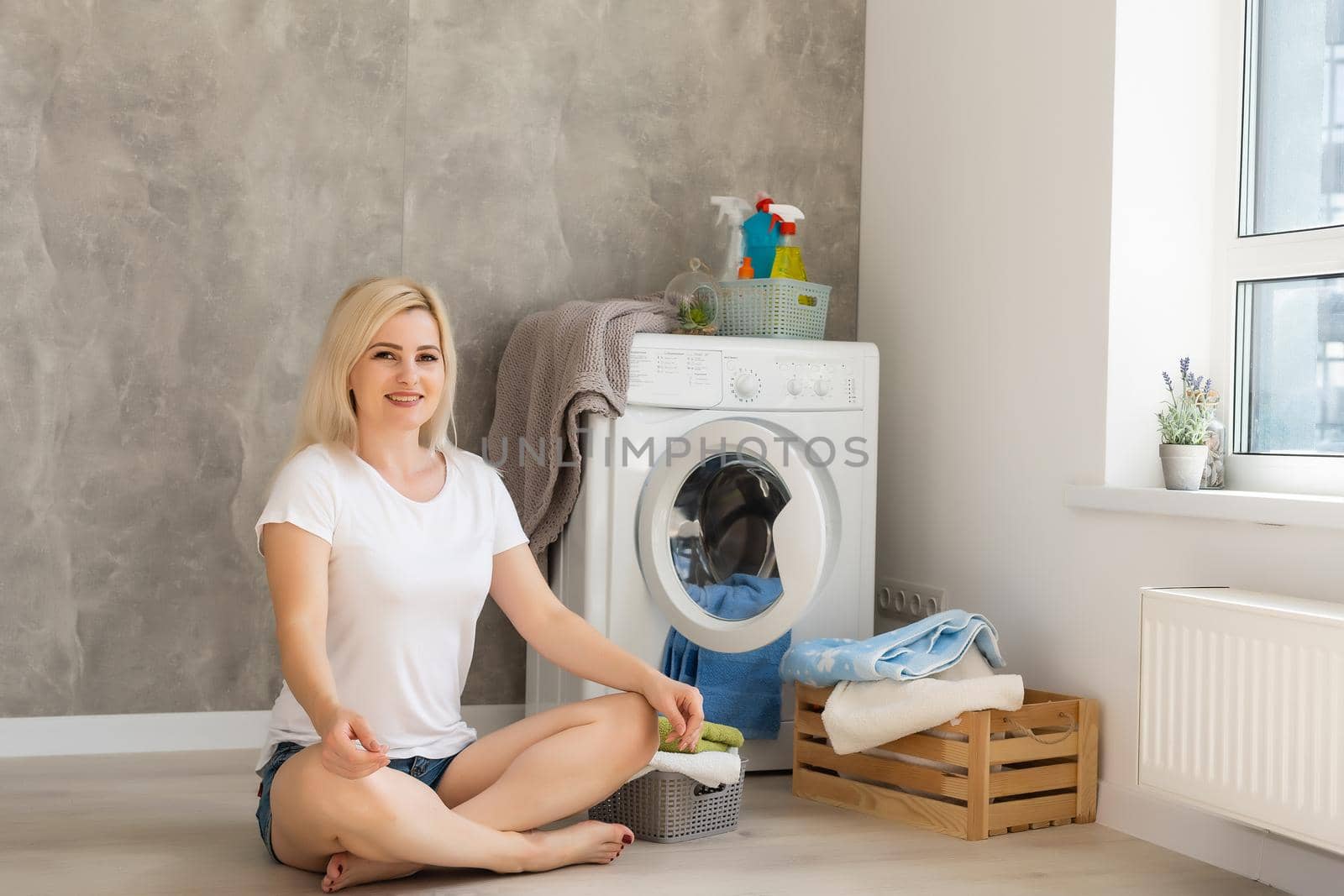 A young housewife with washing machine and clothes. Washing day.