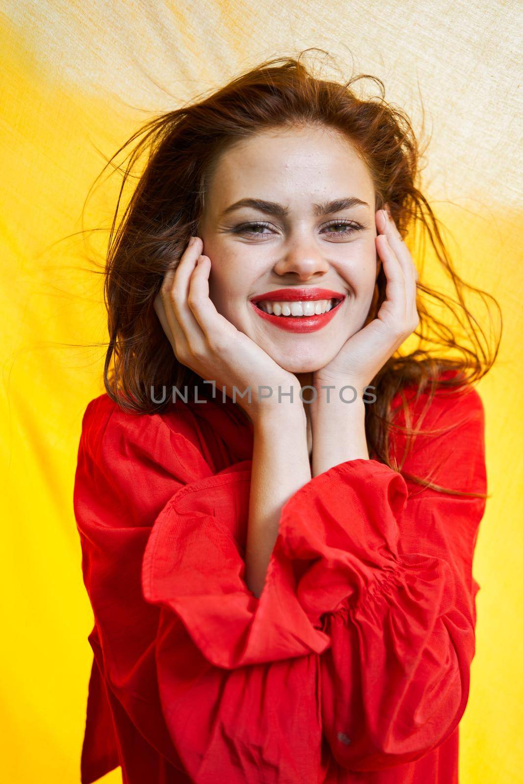 smiling woman in red dress posing yellow background. High quality photo