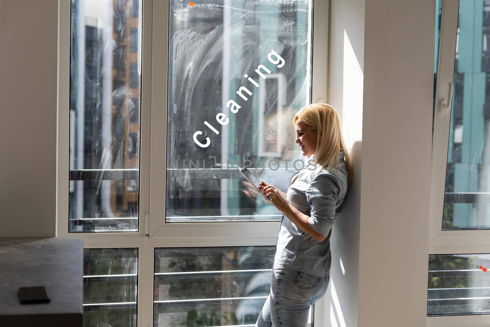 woman with tablet looking for cleaning to wash dirty window