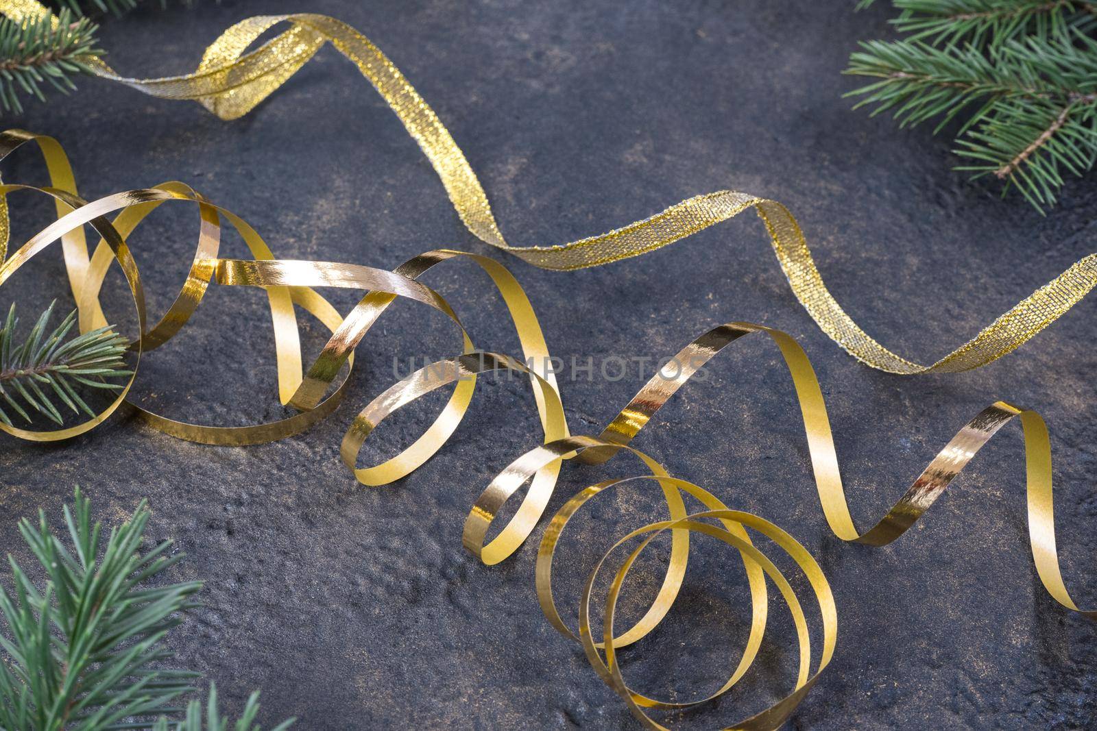 Christmas composition of fir branches and a gold ribbon on a black oil with gold embossing background. by Ekaterina34