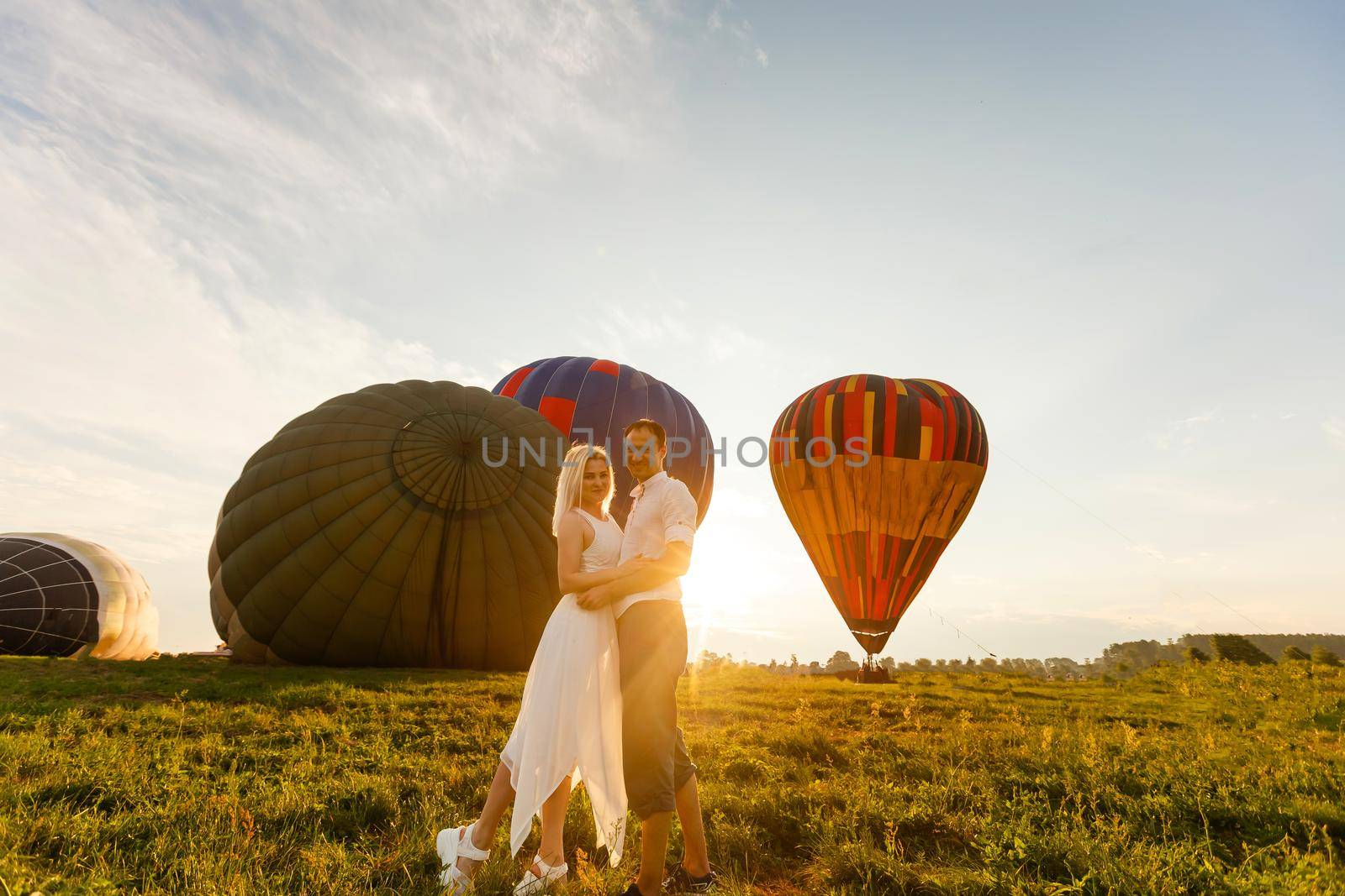 Beautiful romantic couple hugging at meadow. hot air balloon on a background by Andelov13