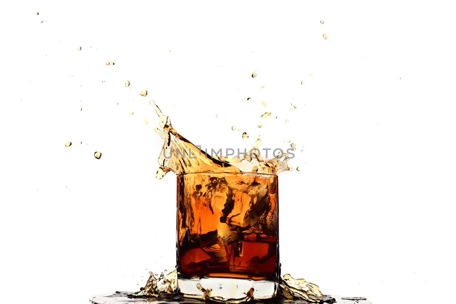 Ice cube falling into whiskey in glass isolated on white