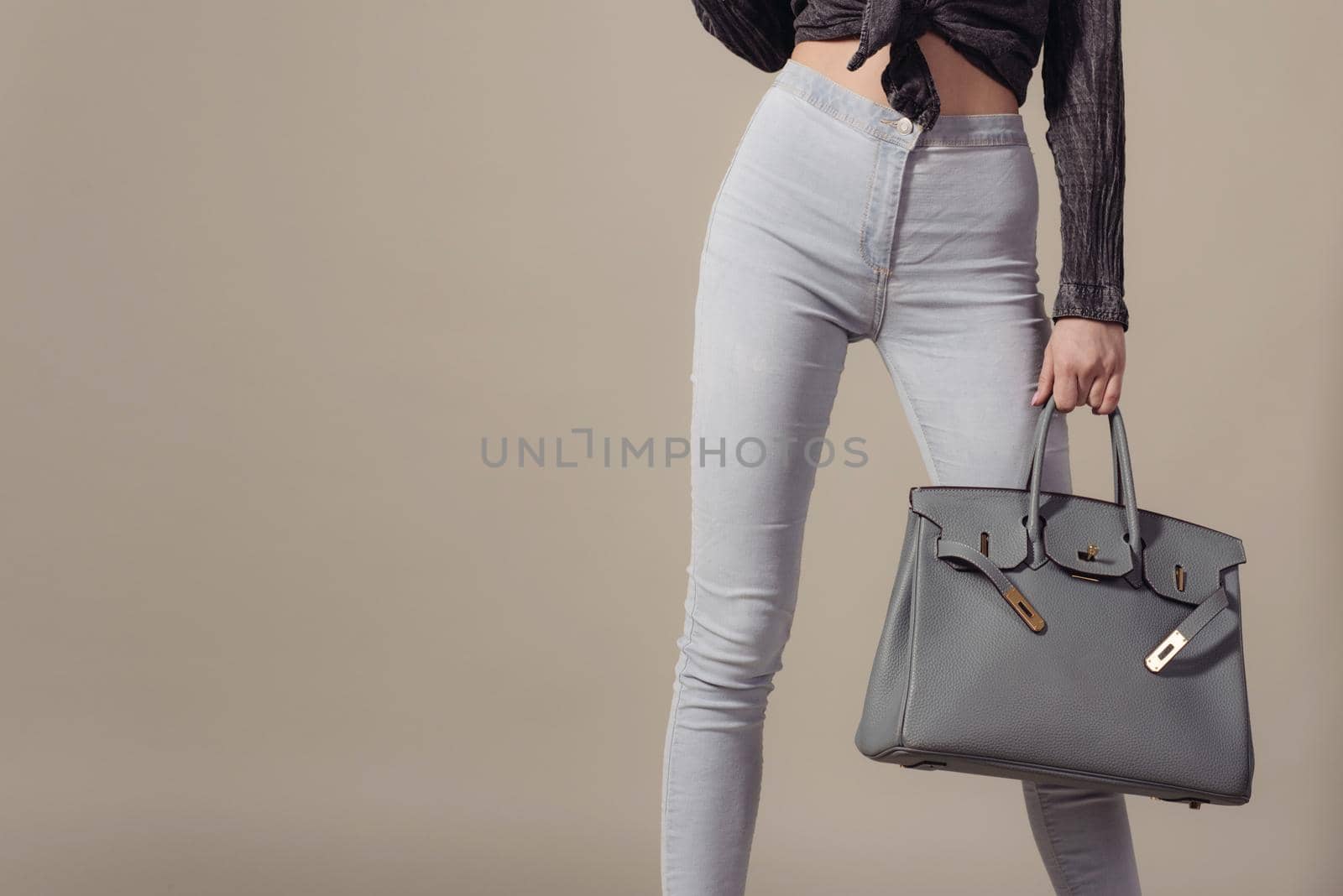 Close up woman with stylish leather big bag in hand on gray background