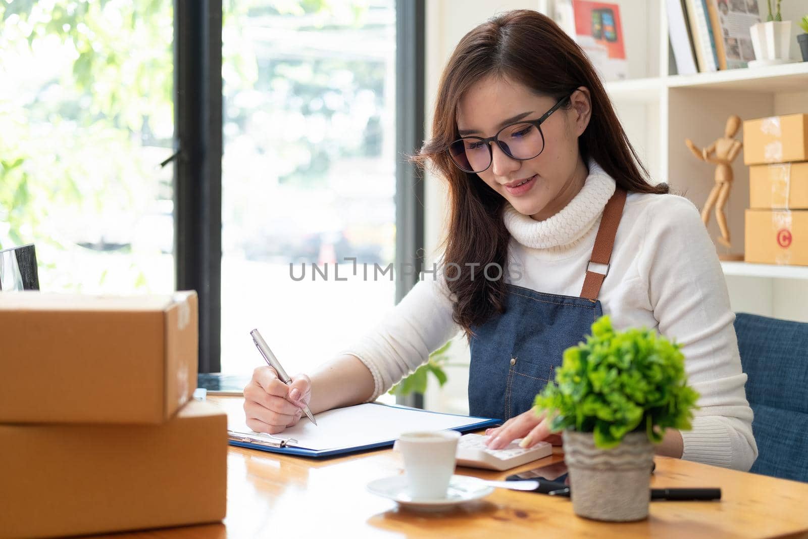 Starting Small business entrepreneur SME freelance,Portrait young woman working at home office, BOX,smartphone,laptop, online, marketing, packaging, delivery, SME, e-commerce concept