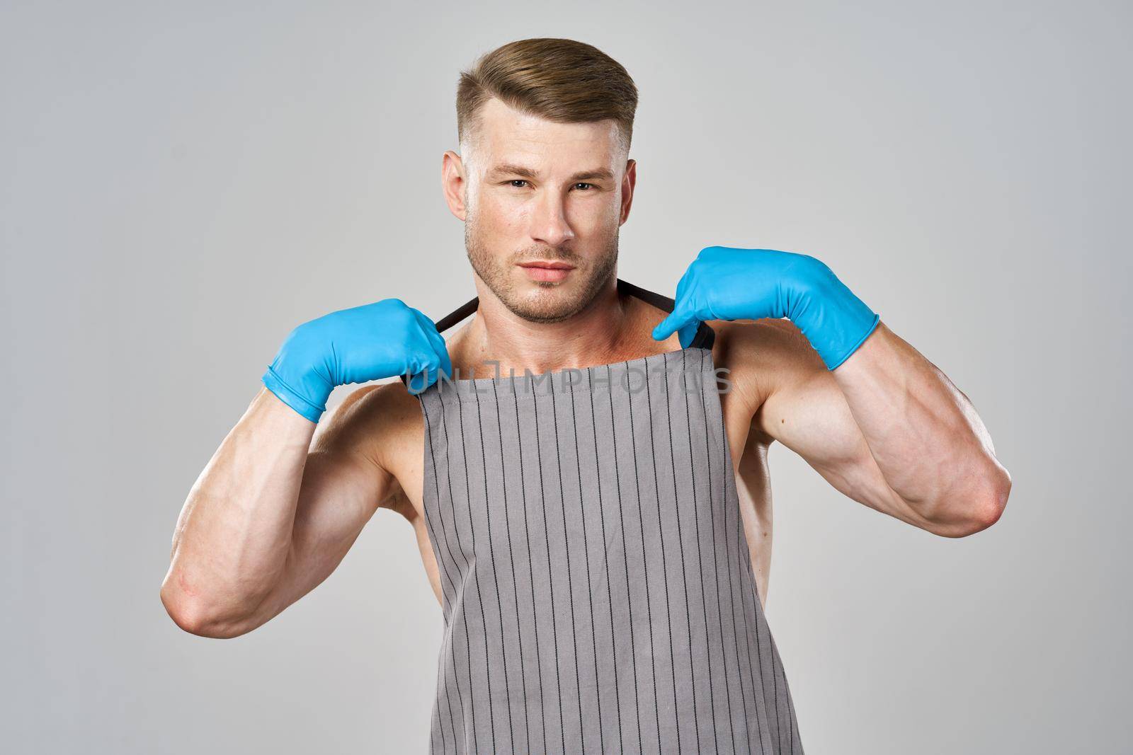 pumped up man in apron wearing rubber gloves posing cleaner. High quality photo