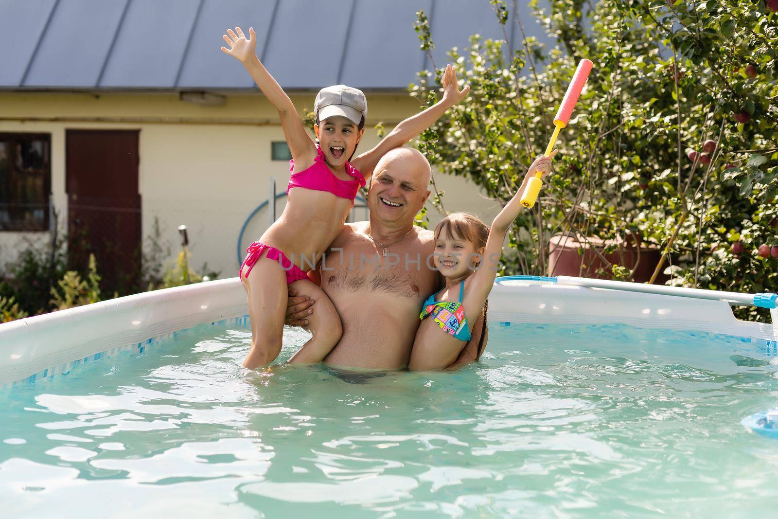 Grandfather with grandchildren girl jumping into a pool of water by Andelov13