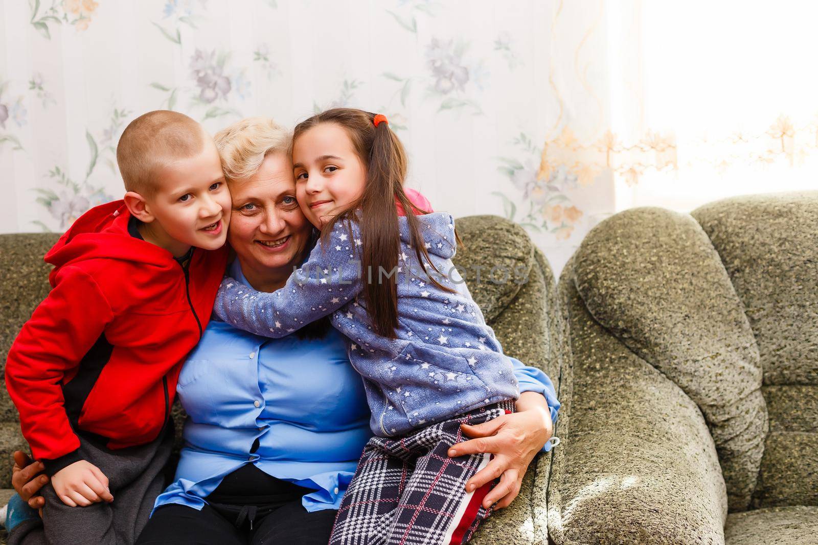 Grown up adult smiling grandchildren embraces elderly grandmother glad to see missing her, visit of loving relatives enjoy communication, cuddle as symbol of connection, love and support concept by Andelov13