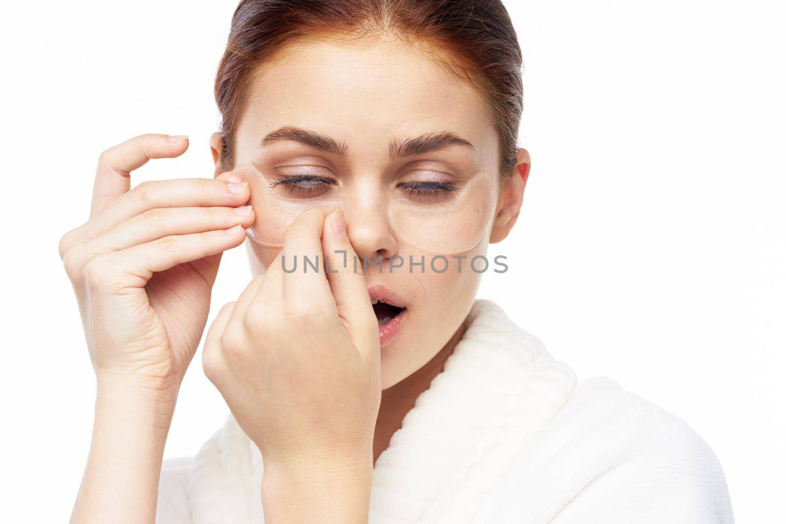 Woman in white robe posing fun skin care patches on face. High quality photo