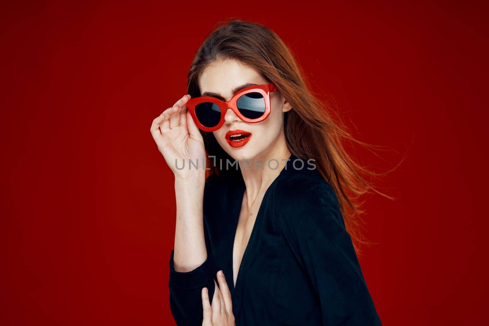 pretty woman wearing sunglasses fashion posing hairstyle red background. High quality photo