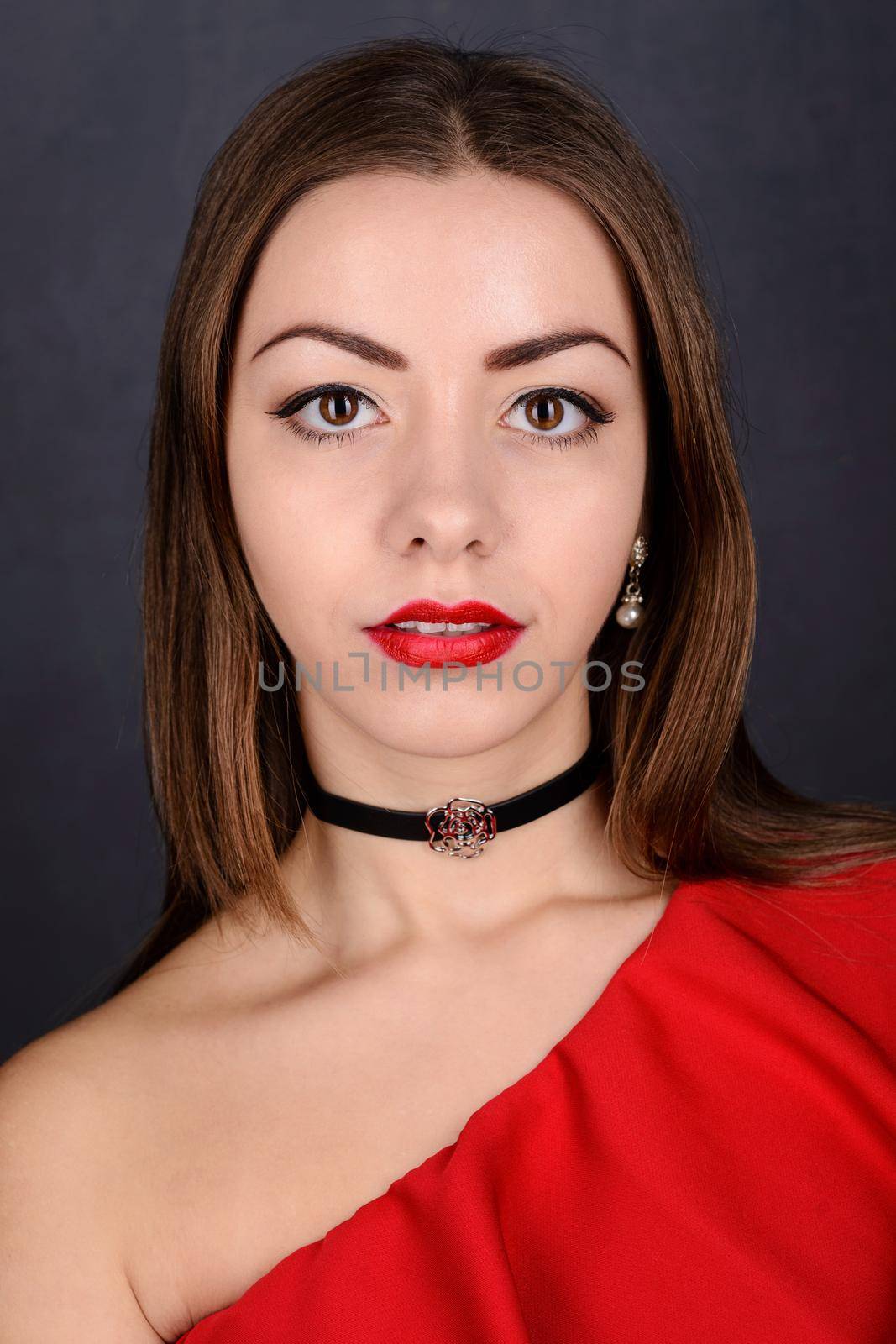 Beautiful young elegant woman in sexy red dress on dark background