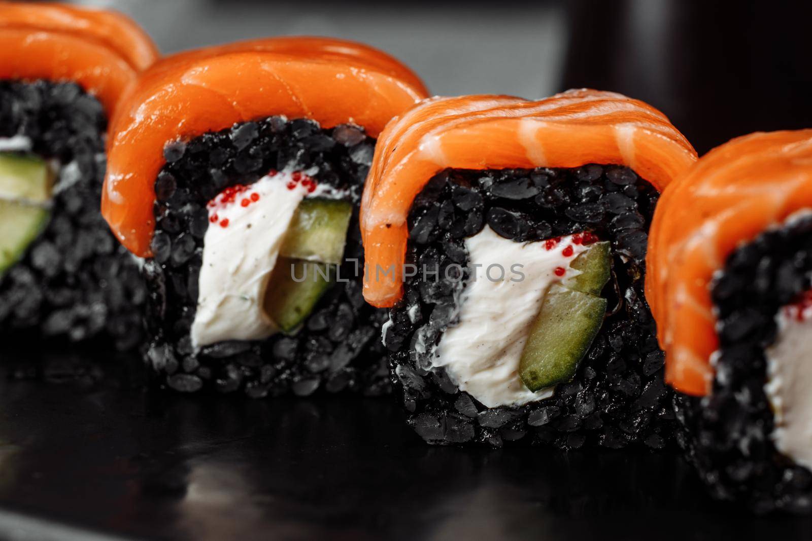 A set of sushi rolls Philadelphia with red fish, cream cheese and black rise lies in a plate boat. Sushi rolls on a gray background by UcheaD